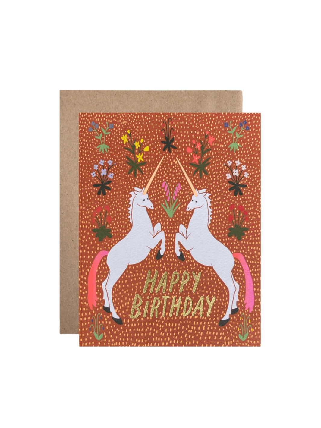 The Happy Birthday Unicorns Card from Hartland Cards features two rearing white unicorns with pink tails facing each other on a textured rust-colored floral background with gold glitter text, paired with a brown kraft envelope | Twentyseven Toronto