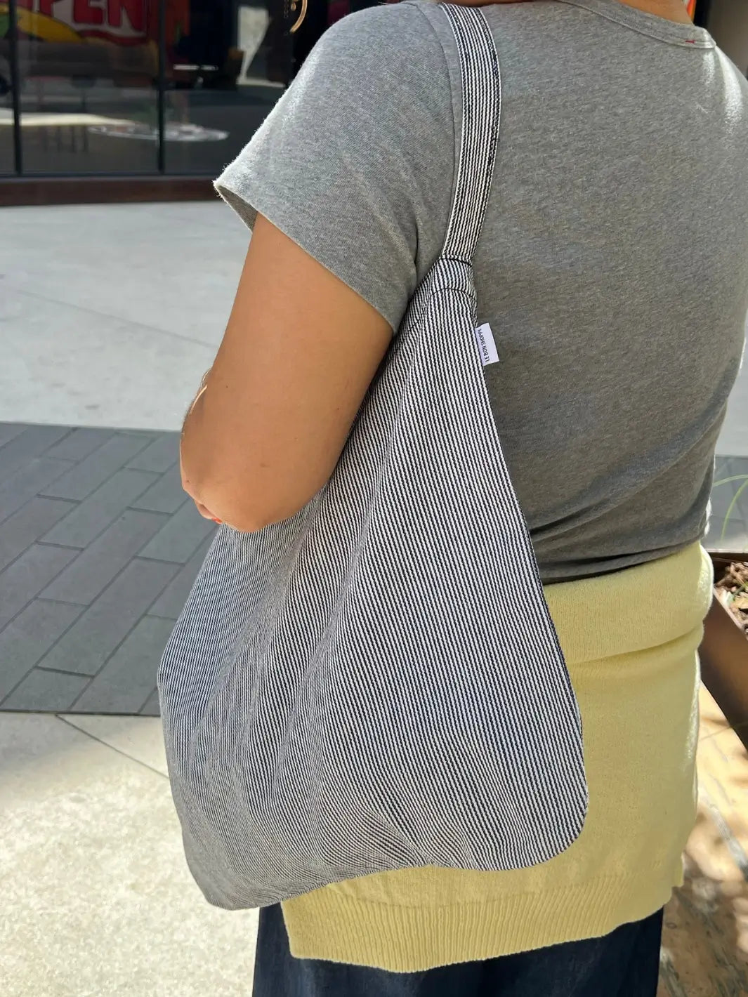 Person holding a Le Bon Shoppe tote bag in 'Blue Stripe' design outdoors | Twentyseven Toronto