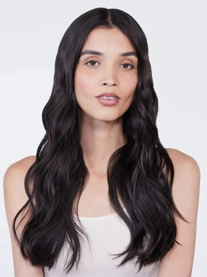 A front portrait shows a woman with beautifully defined, glossy dark waves following a wash with Hair by Sam McKnight Light Cleanse Hair & Scalp Shampoo | Twentyseven Toronto