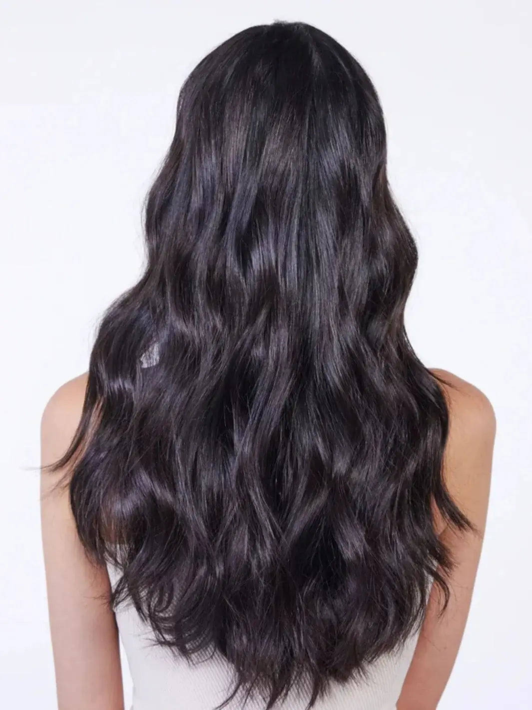 A rear view highlights the intense shine and smooth texture of a woman's long, wavy dark hair styled after using Hair by Sam McKnight Light Cleanse Hair & Scalp Shampoo | Twentyseven Toronto