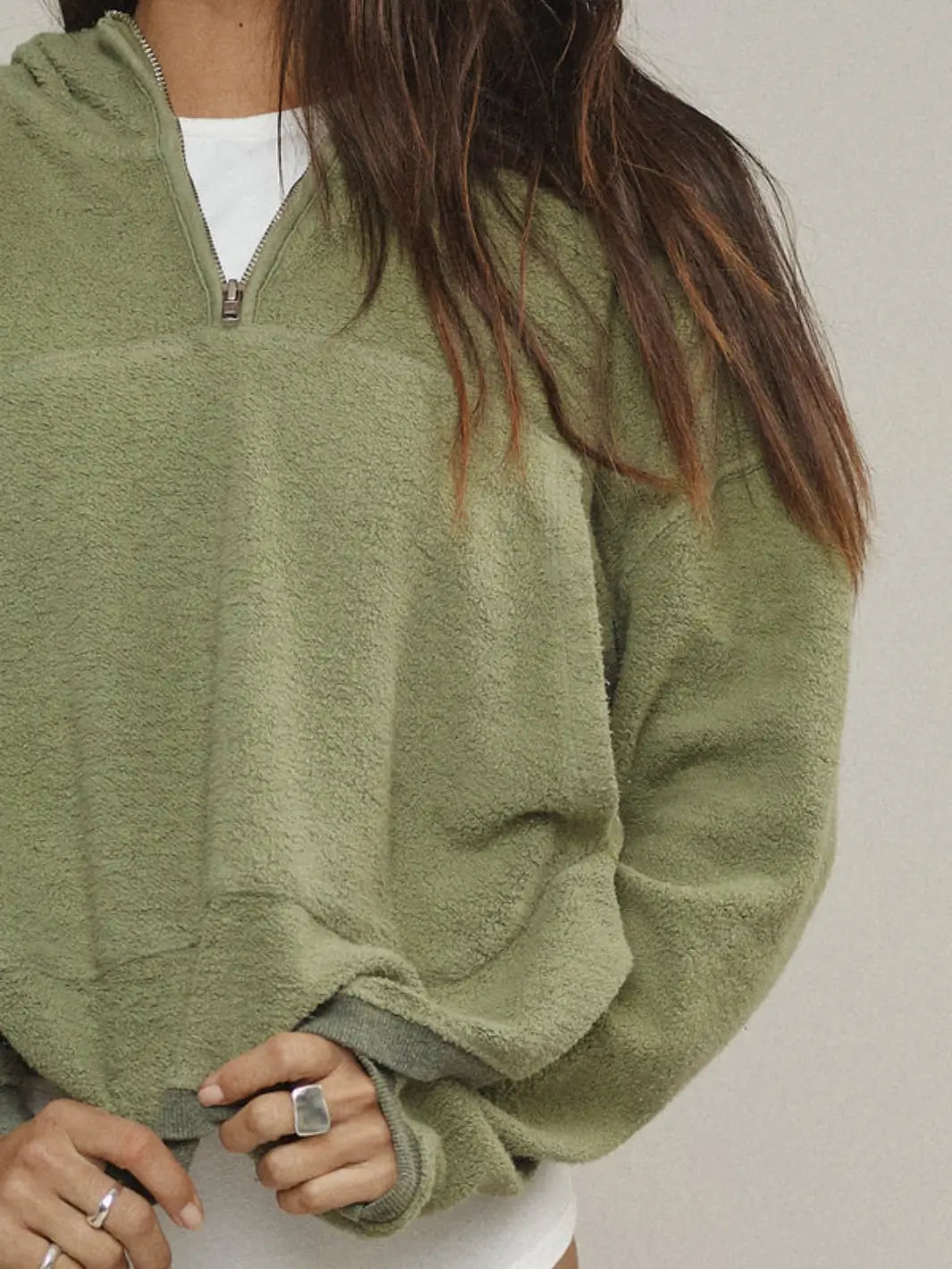 A detailed close-up focuses on the textured material, zipper closure, and ribbed cuffs of the Jungmaven Heathered Osprey Cropped Sweatshirt - Olive Green | Twentyseven Toronto