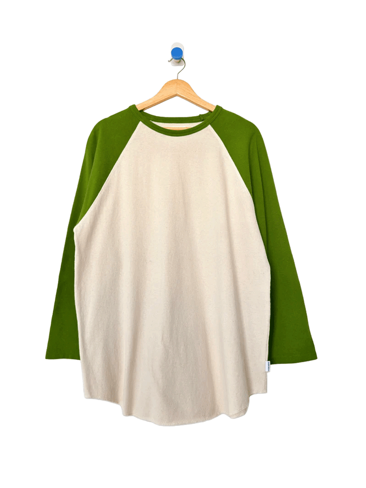 Heavy Cotton Raglan Tee in Naturel/Collard Green displayed on a wooden hanger, featuring a cream body, contrasting green raglan sleeves, crew neckline and relaxed fit | Twentyseven Toronto