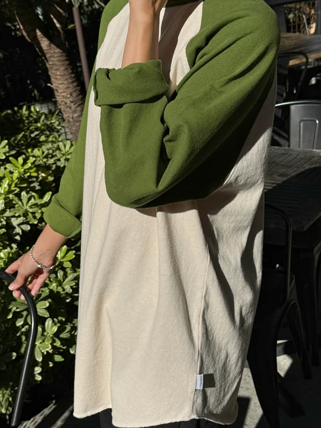 Side view of Heavy Cotton Raglan Tee in Naturel/Collard Green featuring contrasting olive green raglan sleeves, a cream body and loose fit with a curved hem | Twentyseven Toronto