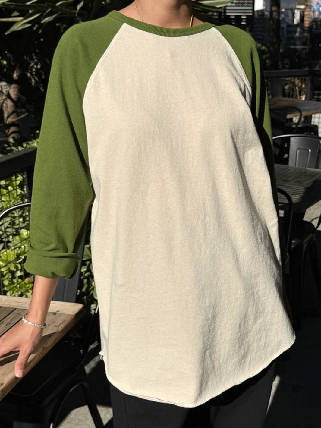 Front view of model wearing Heavy Cotton Raglan Tee in Naturel/Collard Green with a cream body, olive green long sleeves and relaxed silhouette, styled with black pants | Twentyseven Toronto