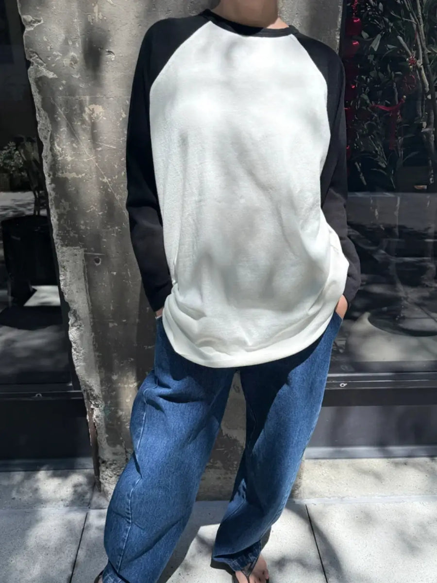 A model poses outdoors wearing the oversized Le Bon Shoppe Heavy Cotton Raglan Tee in White/Black paired with relaxed blue jeans | Twentyseven Toronto