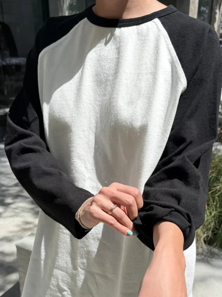 A close-up shot shows a model pulling up the long, black sleeve of the Le Bon Shoppe Heavy Cotton Raglan Tee in White/Black | Twentyseven Toronto