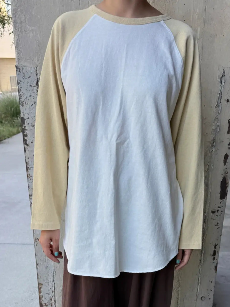 A model stands facing forward to showcase the oversized, loose fit of the white and yellow long-sleeved Le Bon Shoppe Heavy Cotton Raglan Tee in White/Butter | Twentyseven Toronto