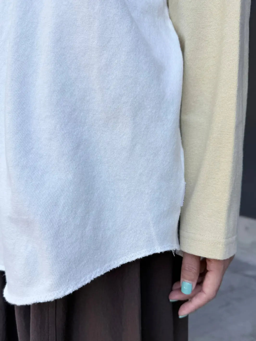 A close-up shot focuses on the raw, unfinished bottom hem and soft knit texture of the Le Bon Shoppe Heavy Cotton Raglan Tee in White/Butter | Twentyseven Toronto