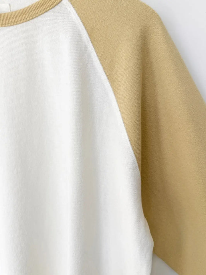A detailed macro shot highlights the contrasting diagonal seam where the butter-yellow sleeve meets the white bodice of the Le Bon Shoppe Heavy Cotton Raglan Tee in White/Butter | Twentyseven Toronto