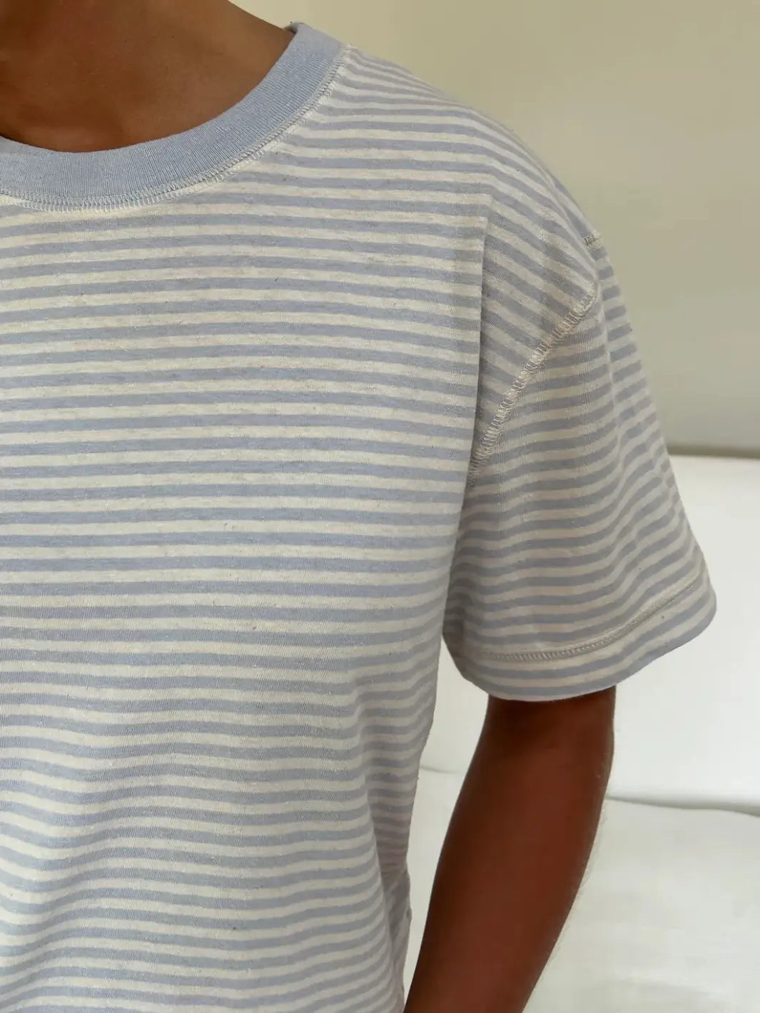 A detailed close-up highlights the horizontal blue and white pinstripe pattern and stitched shoulder details of the Merge Goods Hemp Rover Tee in Daydream Stripes | Twentyseven Toronto