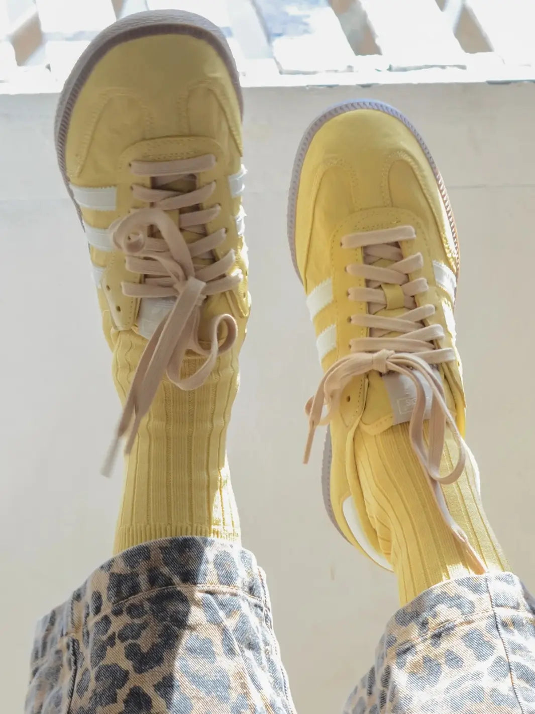 Person wearing mustard yellow Her Socks in 'Buttercup' from Le Bon Shoppe and yellow sneakers against a cream background | Twentyseven Toronto