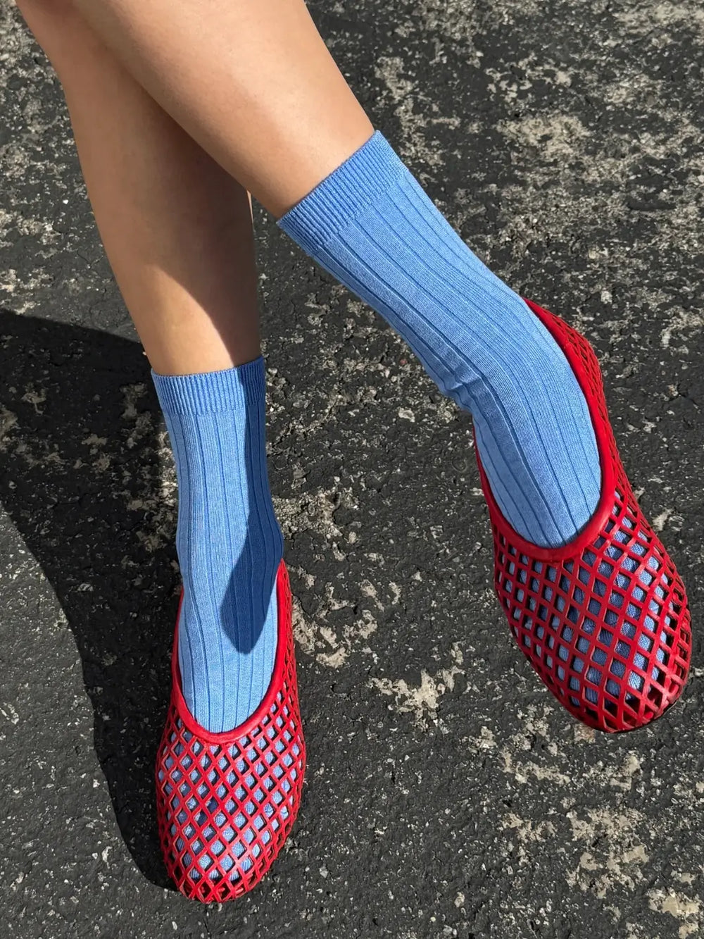 Person wearing blue Le Bon Shoppe Her Socks in Periwinkle and red mesh flats on a dark grey pavement | Twentyseven Toronto