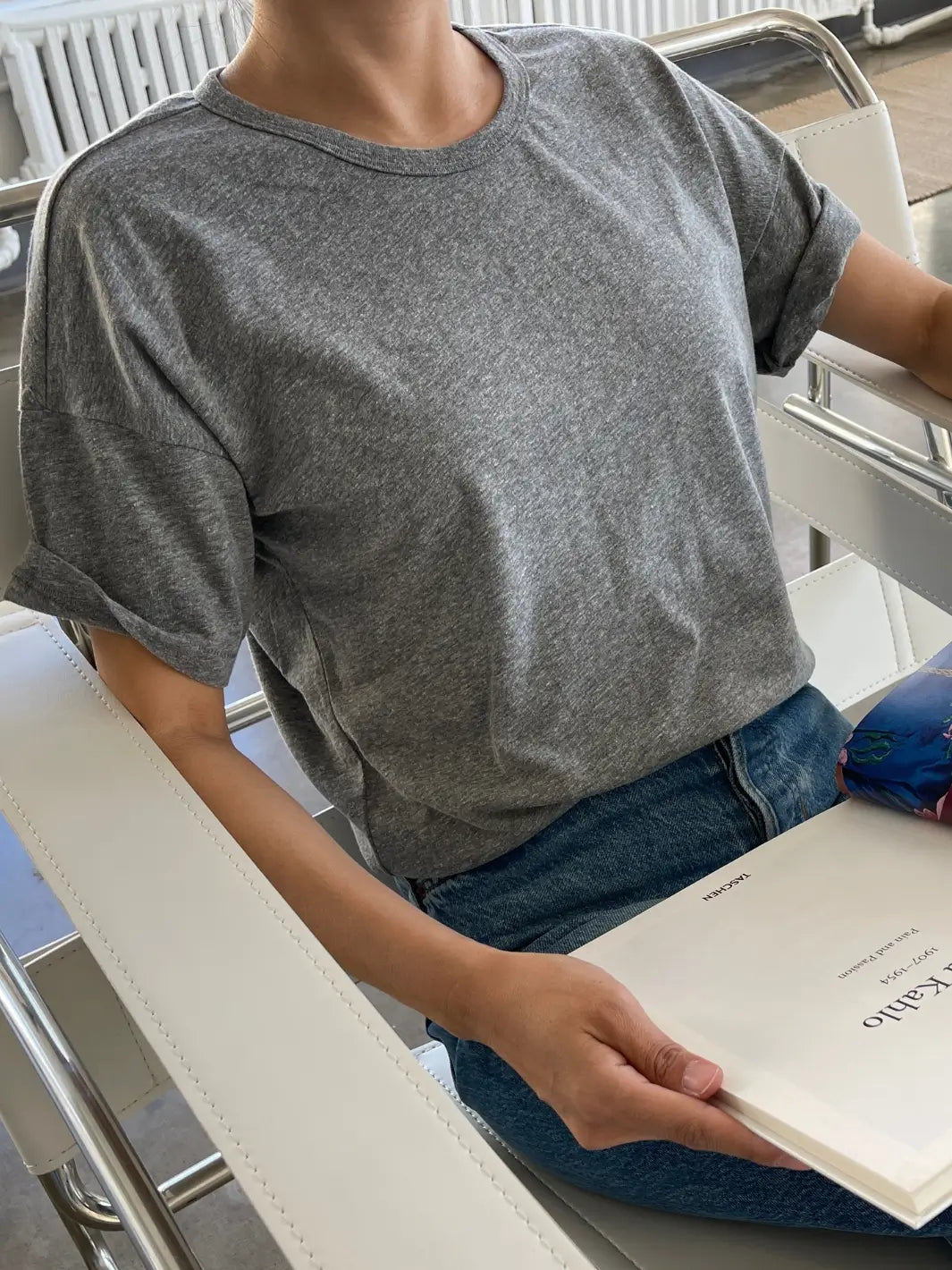 Person wearing a grey Her Tee shirt in 'HT Grey' from Le Bon Shoppe sitting indoors with an open book | Twentyseven Toronto