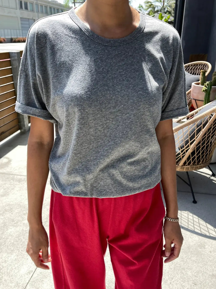 Person wearing a grey Her Tee shirt in 'HT Grey' from Le Bon Shoppe and red pants standing outdoors on a balcony | Twentyseven Toronto