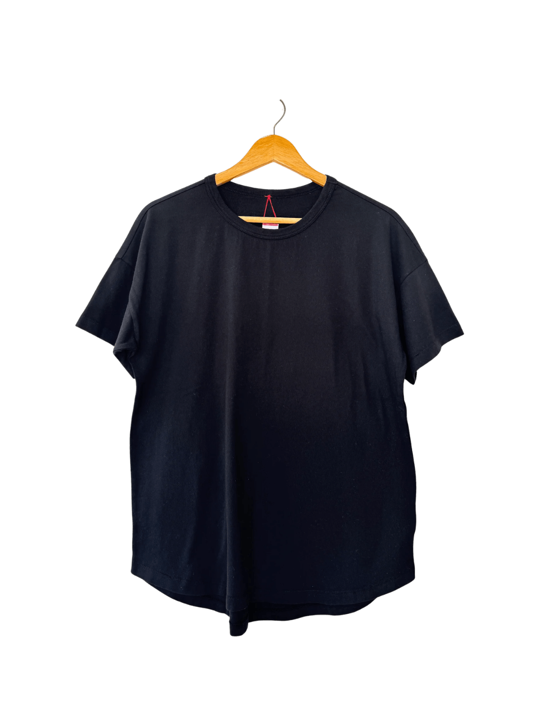 The Le Bon Shoppe Her Tee - True Black is displayed flat on a wooden hanger highlighting its curved hemline | Twentyseven Toronto
