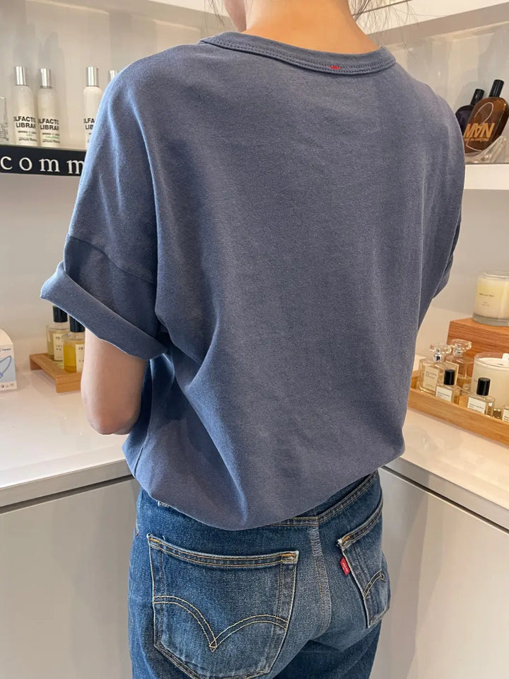 Back side of a person wearing a blue Her Tee in 'Vintage Navy' from Le Bon Shoppe and blue jeans standing indoors with products in the background | Twentyseven Toronto