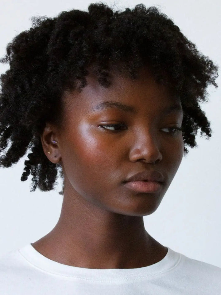 A model showcases a hydrated, frizz-free curly hairstyle achieved with R+Co HIGH DIVE Moisture & Shine Crème | Twentyseven Toronto