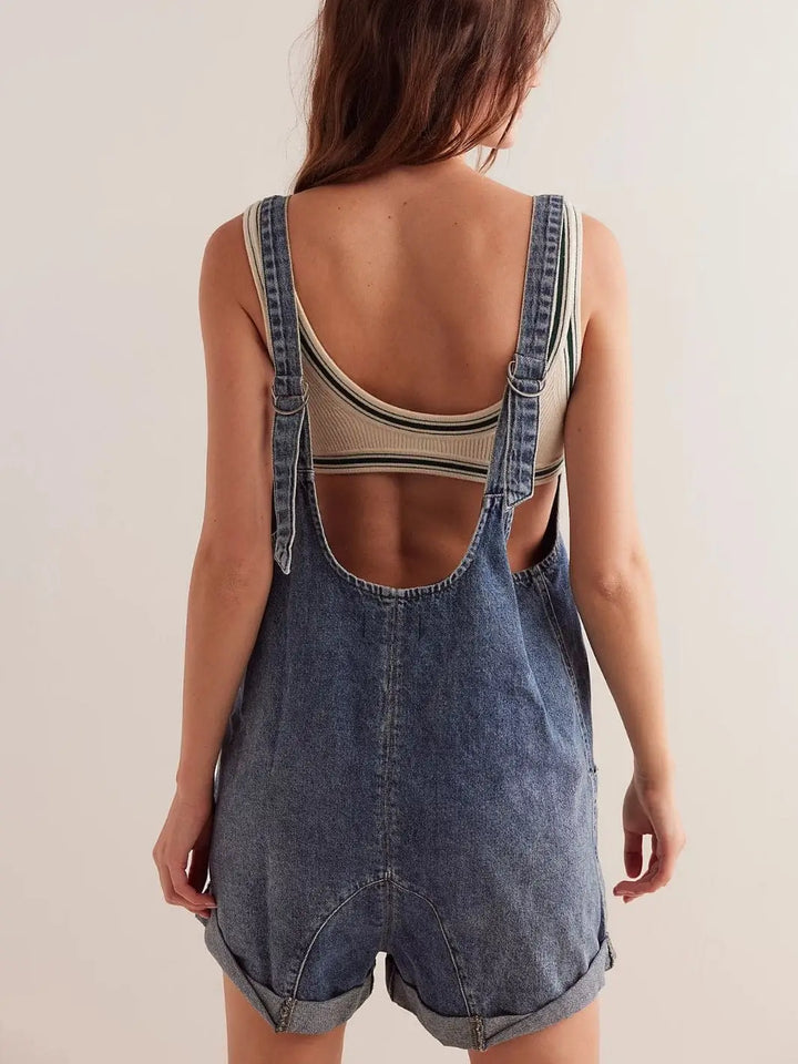 A view from behind highlights the low scoop back, adjustable overall straps, and relaxed fit of the denim Free People High Roller Shortall - Zaza | Twentyseven Toronto