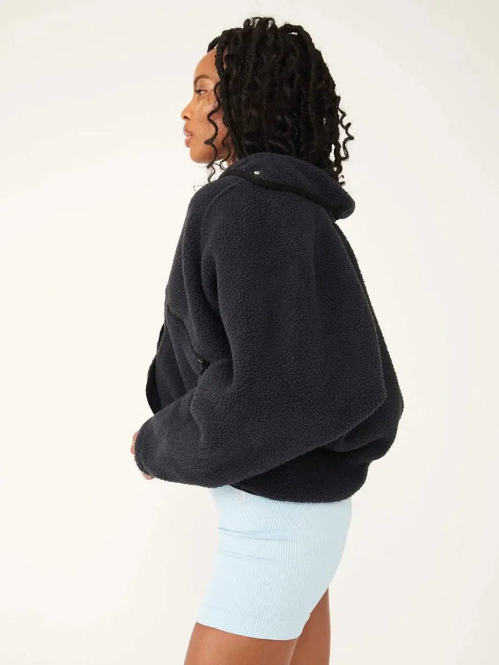 A side profile view highlights the relaxed silhouette and cozy textured fabric of the Free People Hit The Slopes Fleece Jacket - Black | Twentyseven Toronto
