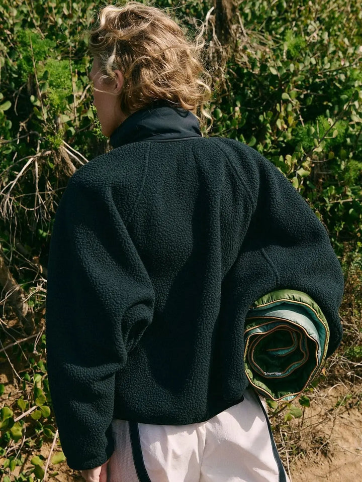 A side angle view showcases the embroidered brand logo detailing near the lower hem of the Free People Hit The Slopes Fleece Jacket - Black | Twentyseven Toronto