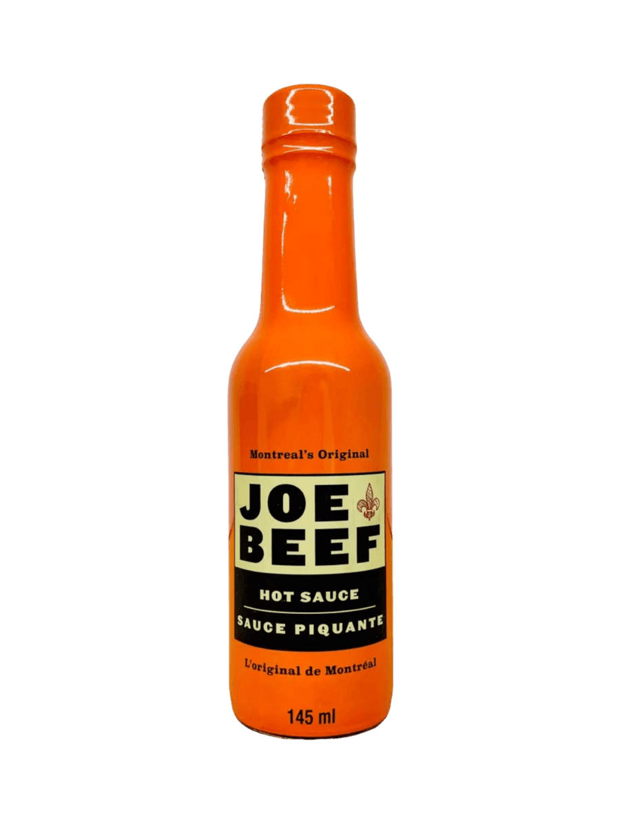 A 145 mL glass bottle filled with a bright orange Hot Sauce Joe Beef condiment features a cream and black label reading "Montreal's Original Joe Beef Hot Sauce Sauce Piquante" | Twentyseven Toronto