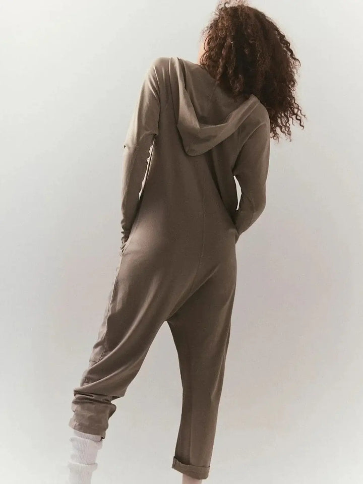 A view from behind highlights the attached hood, loose fit, and dropped crotch design of the Free People Hot Shot Long Sleeve Onesie - Sage Stone | Twentyseven Toronto