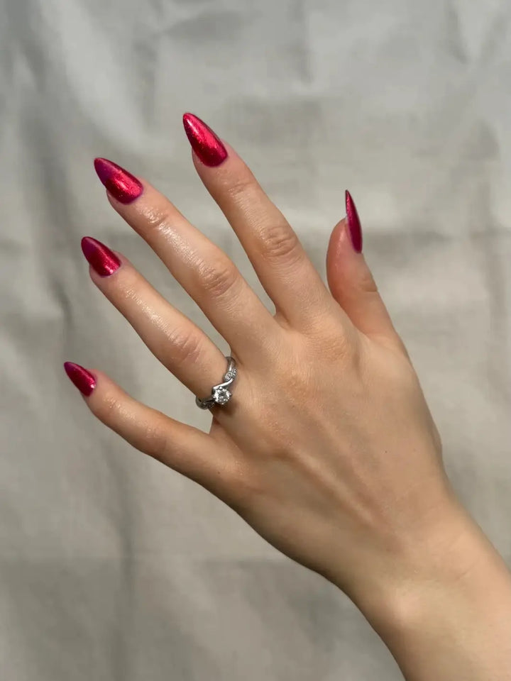 A hand with long, almond-shaped nails painted in a shimmering crimson shade showcases Death Valley Nails Hot Tamale Nail Polish | Twentyseven Toronto