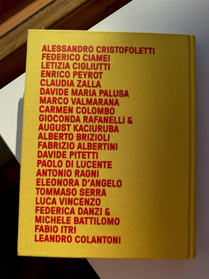Yellow back cover of How Italy Feels: Through the Lens, Region by Region by Italy Segreta, featuring a long list of contributing photographers, including Alessandro Cristofoletti and Federico Ciamei, printed in bold red text | Twentyseven Toronto