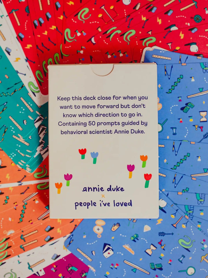 The back of the box for the How To Decide Deck from People I've Loved details its 50 prompts by behavioral scientist Annie Duke, set against a background of scattered, colourful cards | Twentyseven Toronto