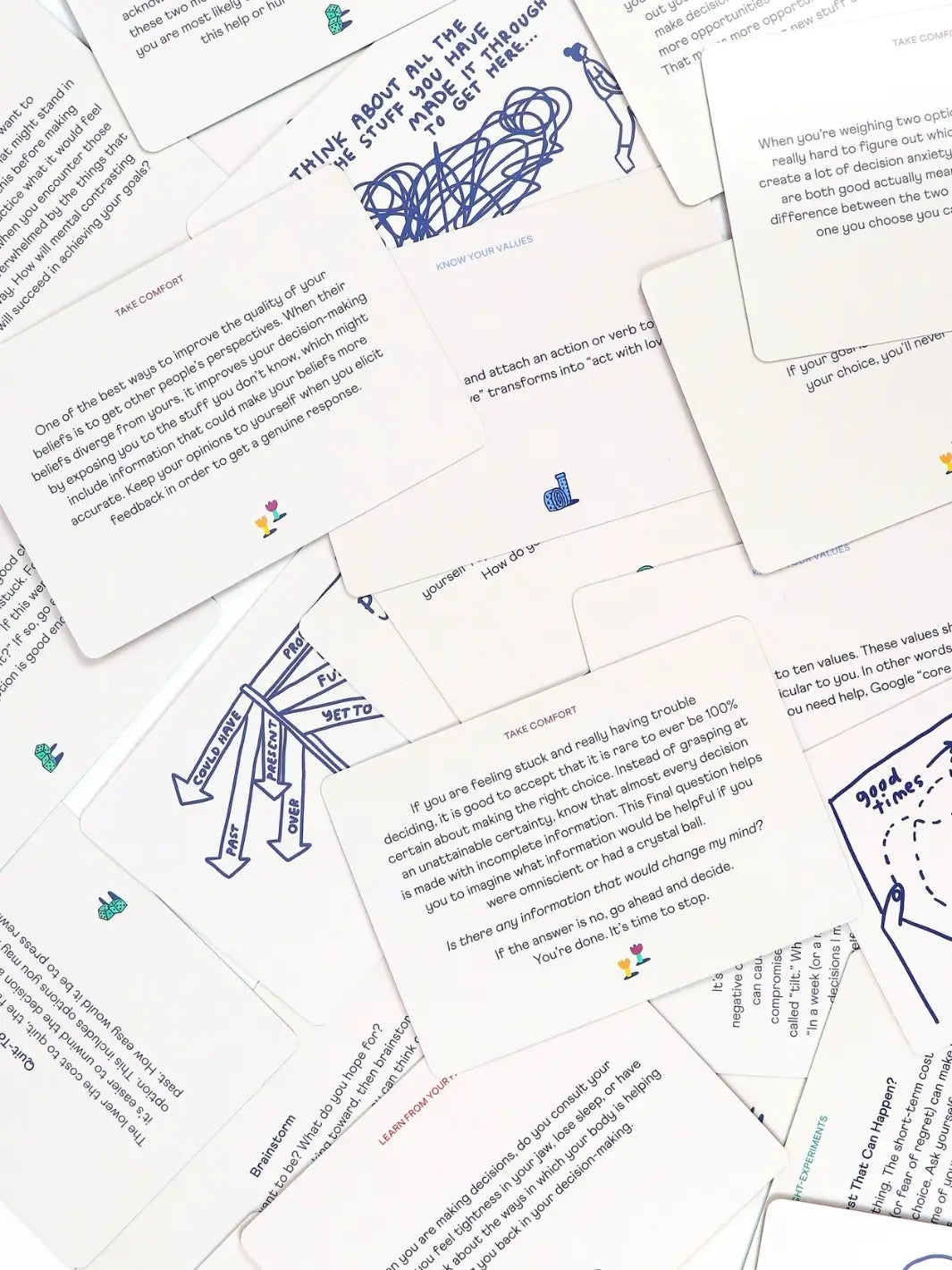 Multiple white text cards from the How To Decide Deck from People I've Loved are scattered, showing thought-experiments and decision-making advice | Twentyseven Toronto