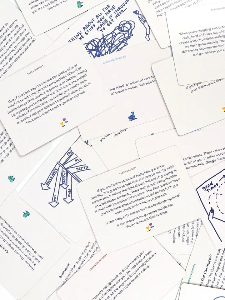 Multiple white text cards from the How To Decide Deck from People I've Loved are scattered, showing thought-experiments and decision-making advice | Twentyseven Toronto
