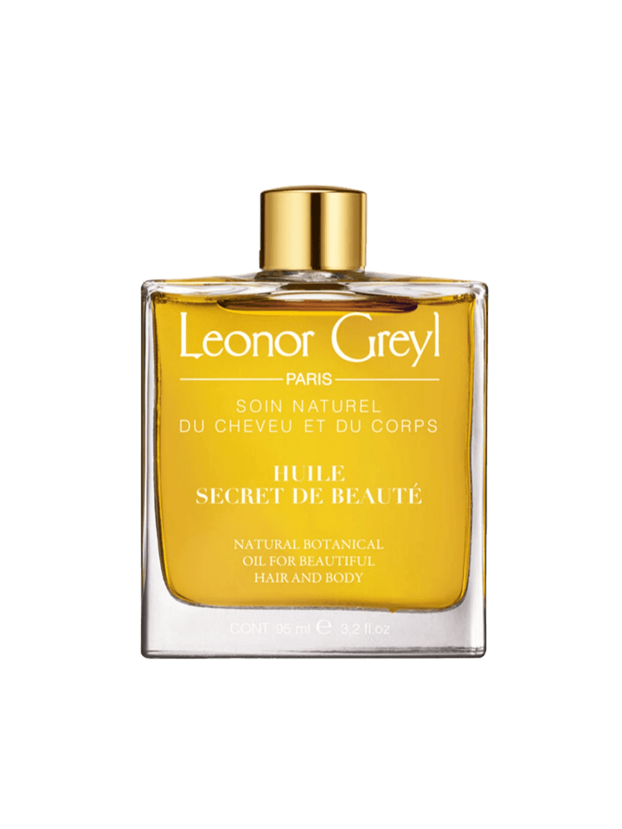 Glass bottle of gold liquid 'Huile Secret de Beauté' by Leonor Greyl on a transparent background | Twentyseven Toronto