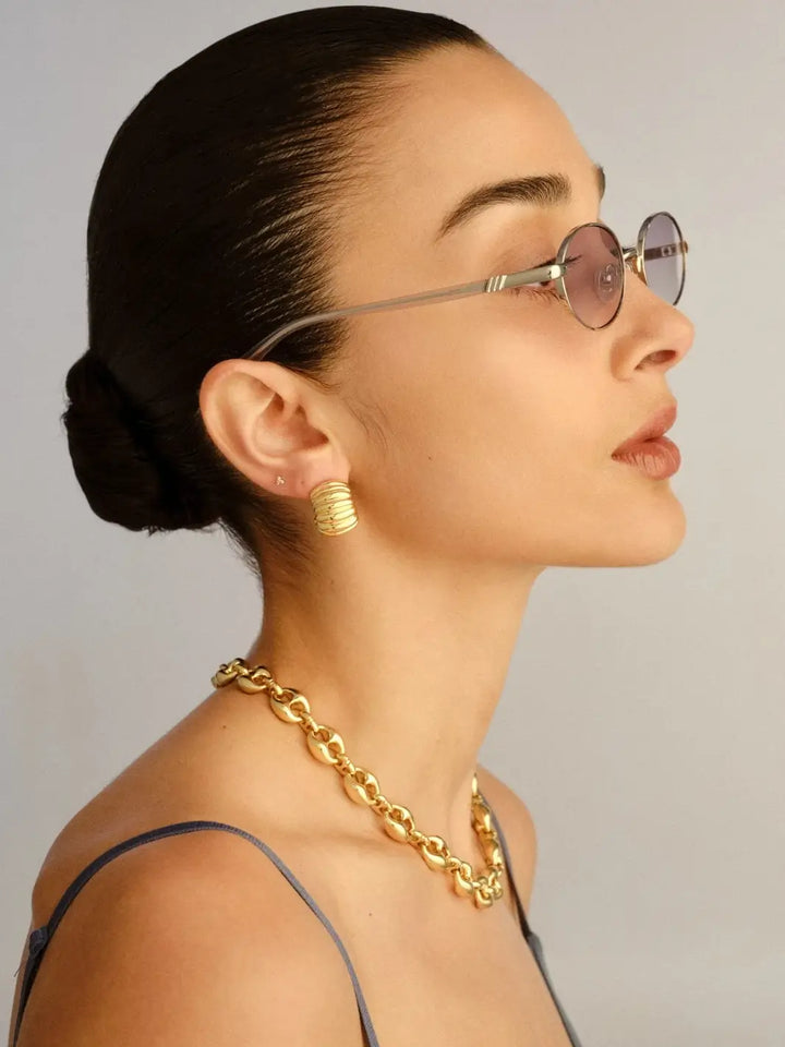 A side-profile studio view of a woman looking to the right to showcase the narrow metal temple arm and clear tip design of the Le Specs Icicle - Silver Smoke Grad sunglasses | Twentyseven Toronto