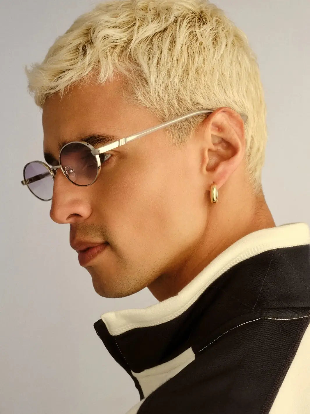 A side-profile studio view of a blonde man looking to the left to highlight the slim frame construction and subtle gradient lenses of the Le Specs Icicle - Silver Smoke Grad sunglasses | Twentyseven Toronto