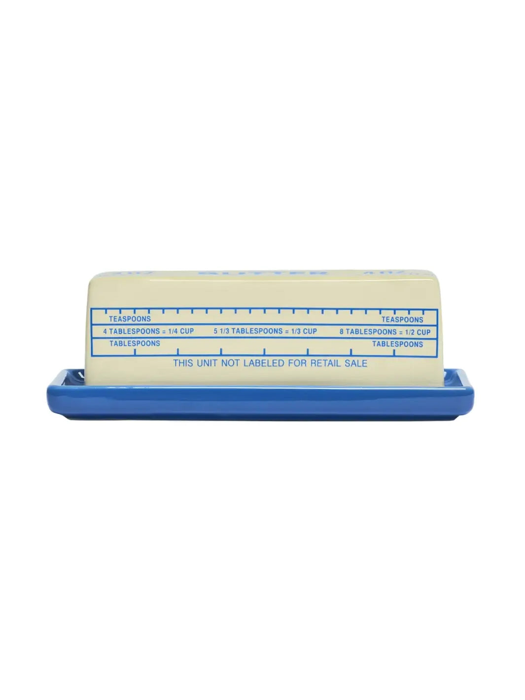 A side view of the ceramic Item - Butter Stick Butter Dish from Fishs Eddy, featuring blue measurement markings for tablespoons and teaspoons on its cream-coloured lid | Twentyseven Toronto