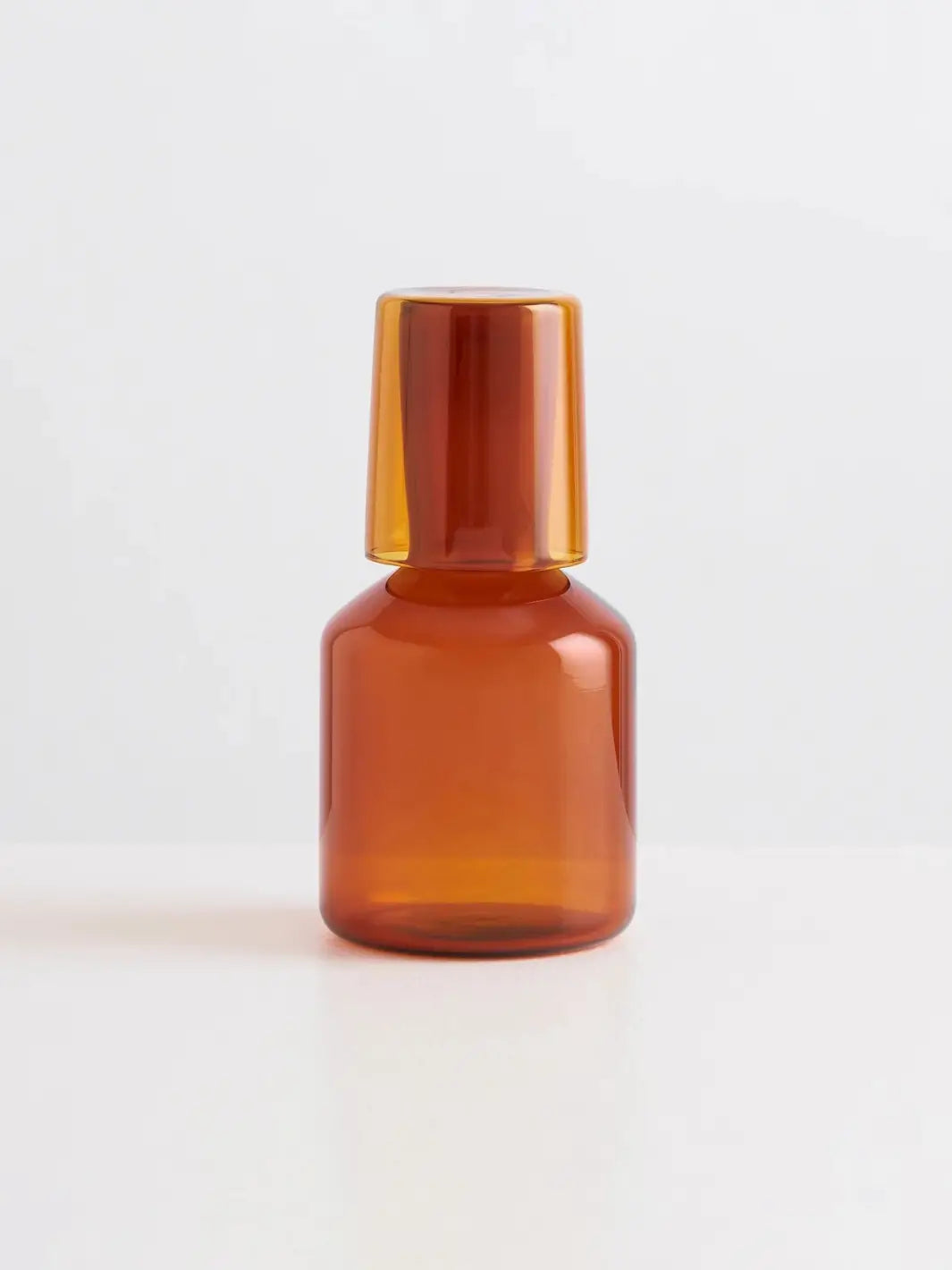 Amber glass 'J'ai Soif' carafe and glass from Maison Balzac on a light gray background | Twentyseven Toronto
