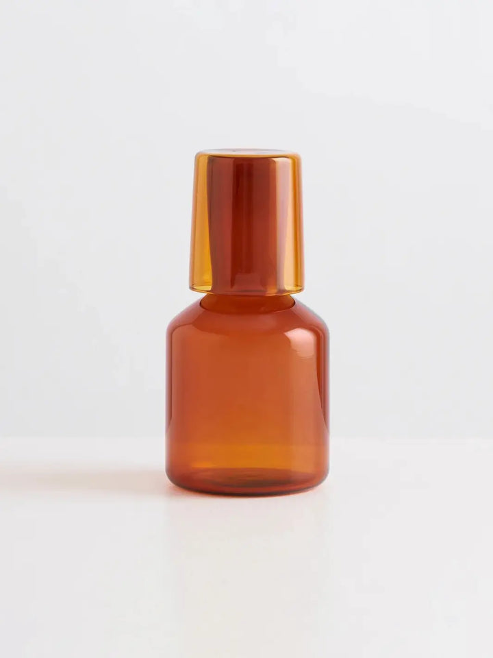 Amber glass 'J'ai Soif' carafe and glass from Maison Balzac on a light gray background | Twentyseven Toronto
