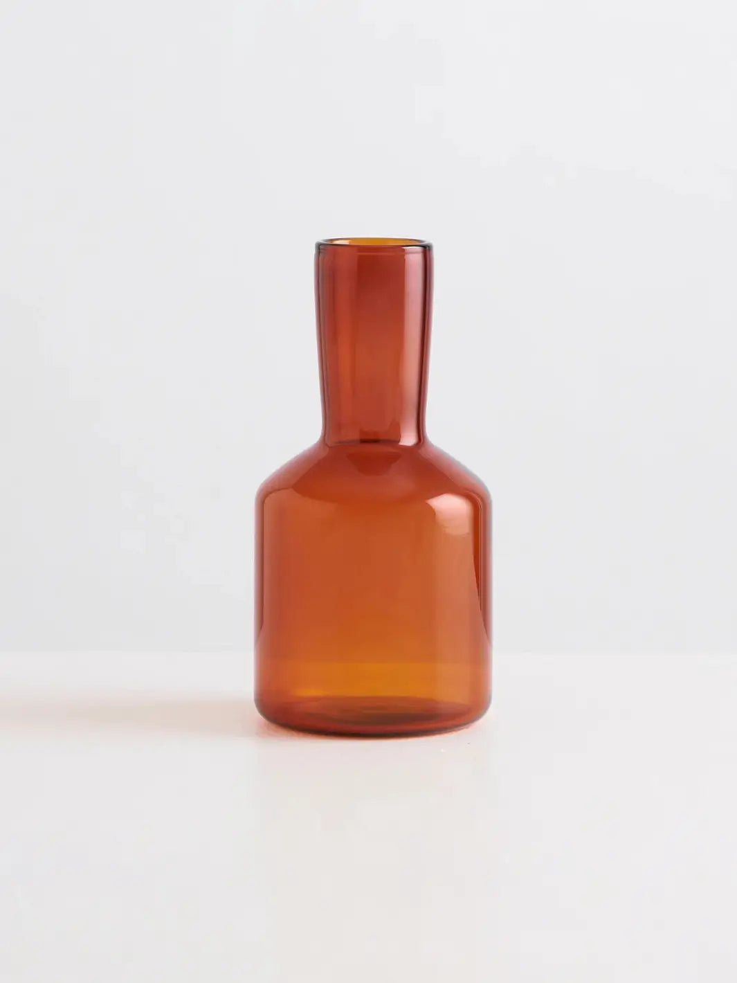Amber glass 'J'ai Soif' carafe and glass from Maison Balzac on a light gray background | Twentyseven Toronto