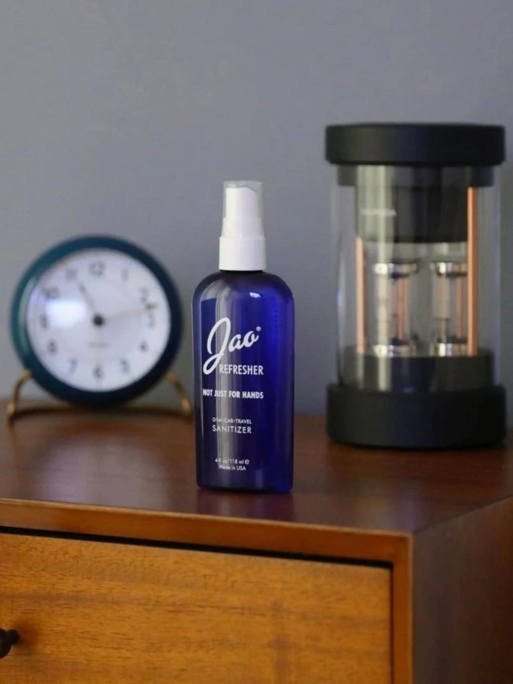 Blue bottle of 2 fl oz Jao Refresher on a wooden surface with a clock and lantern in the background | Twentyseven Toronto