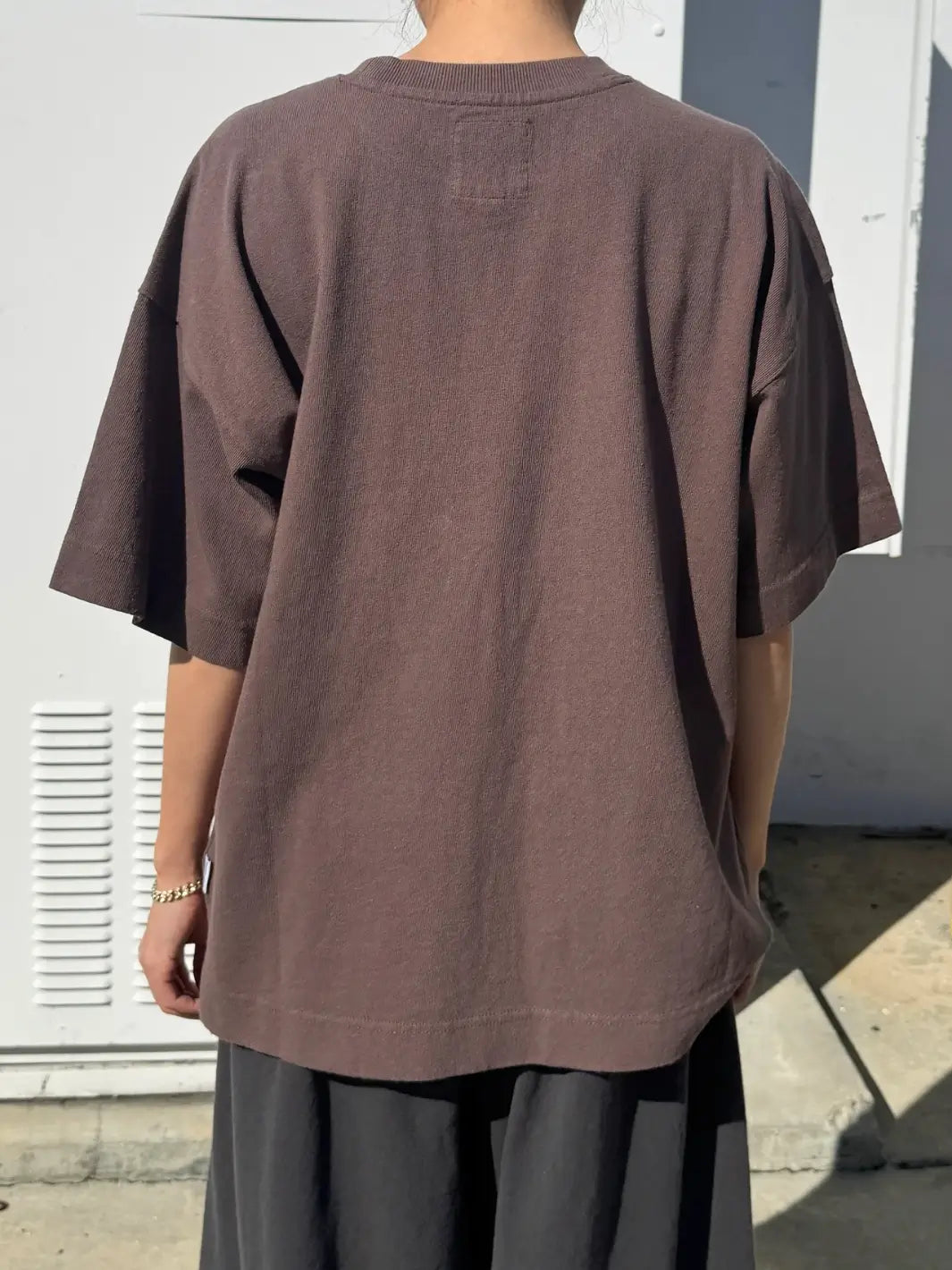 Person wearing dark brown 'Jayden Tee' t-shirt in 'Chocolate' from Le Bon Shoppe with black pants against a white background, back view | Twentyseven Toronto