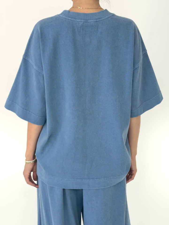 Person wearing blue 'Jayden Tee' t-shirt in 'Cornflower' from Le Bon Shoppe with matching blue pants on a white background, back view | Twentyseven Toronto