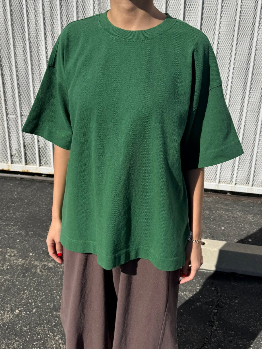Person wearing dark green 'Jayden Tee' t-shirt in 'Moss Green' from Le Bon Shoppe with brown pants in an outdoor setting | Twentyseven Toronto