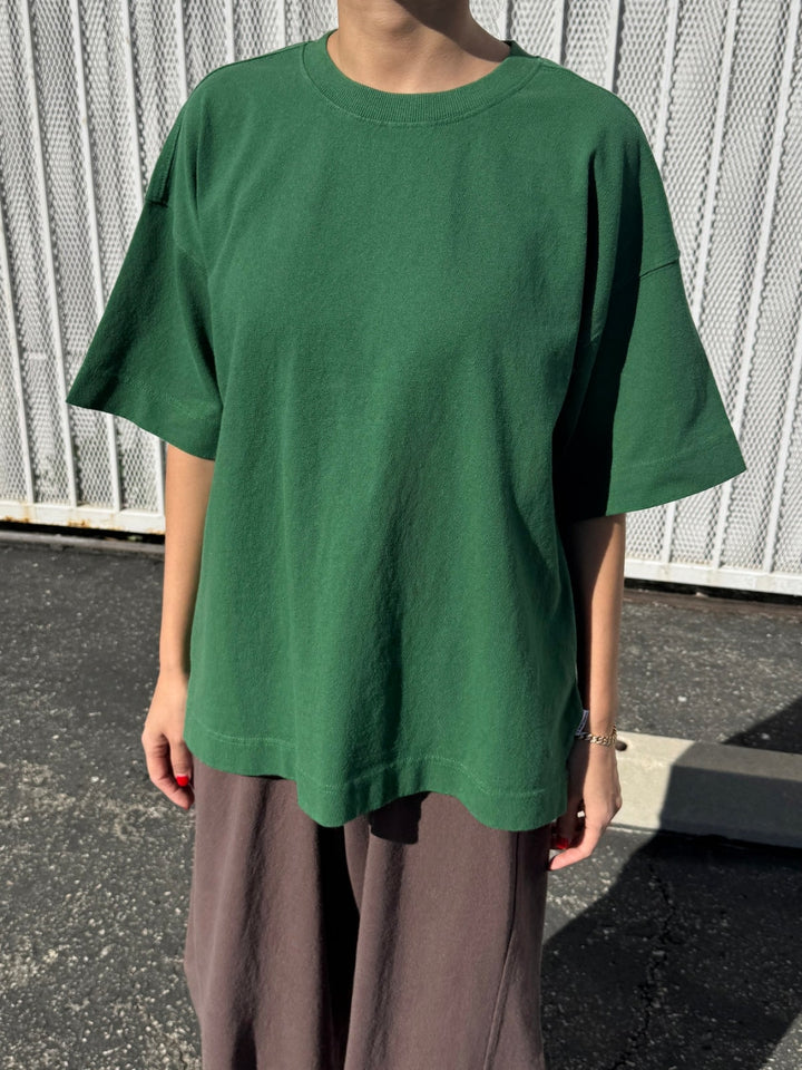 Person wearing dark green 'Jayden Tee' t-shirt in 'Moss Green' from Le Bon Shoppe with brown pants in an outdoor setting | Twentyseven Toronto