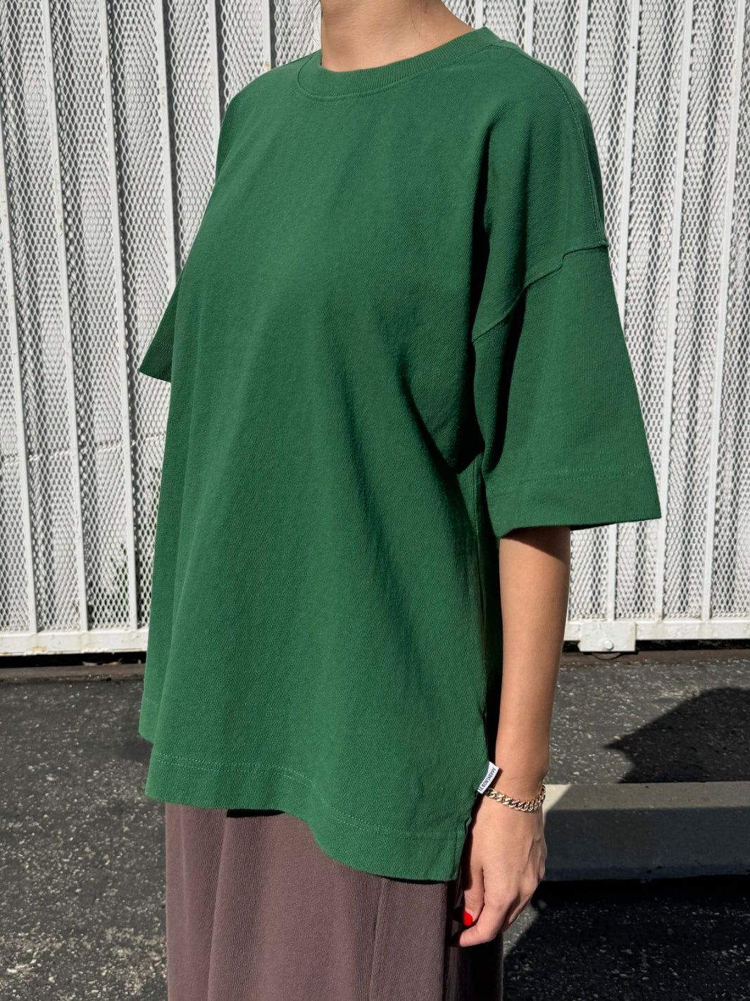 Person wearing dark green 'Jayden Tee' t-shirt in 'Moss Green 'from Le Bon Shoppe with brown pants in an outdoor setting, 45 degree view | Twentyseven Toronto