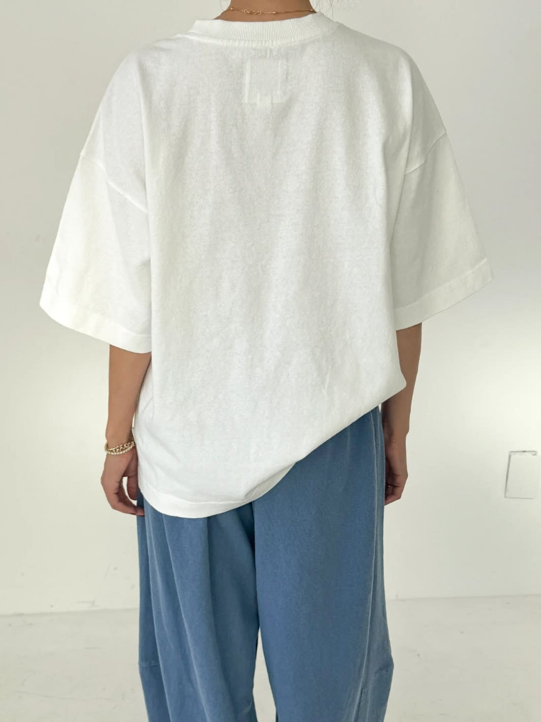 Person wearing white 'Jayden Tee' t-shirt from Le Bon Shoppe with blue pants on a white background, back view | Twentyseven Toronto