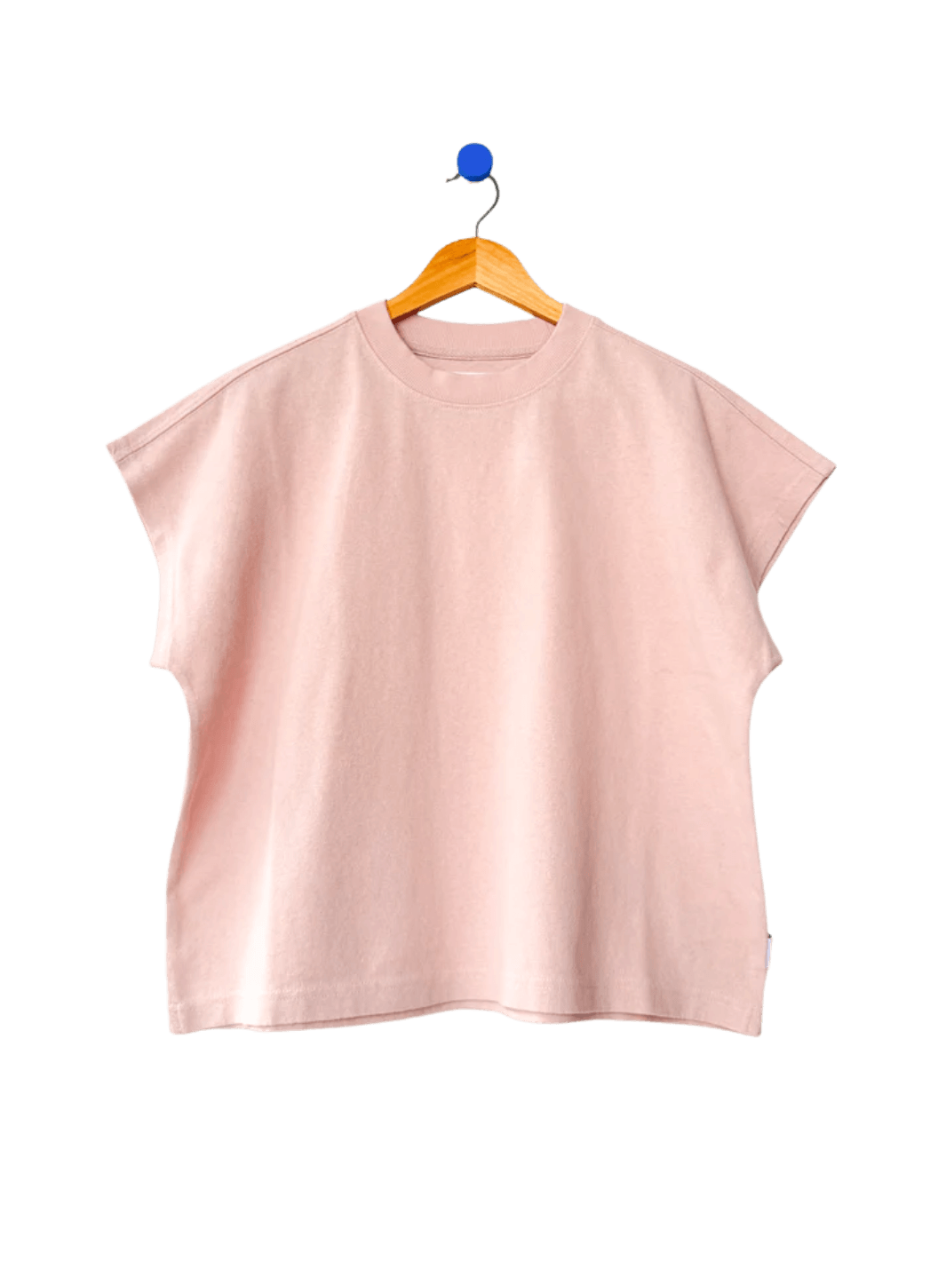 A boxy, crewneck Le Bon Shoppe Jeanne Tee in Baby Pink featuring extended cap sleeves hangs from a wooden hanger | Twentyseven Toronto