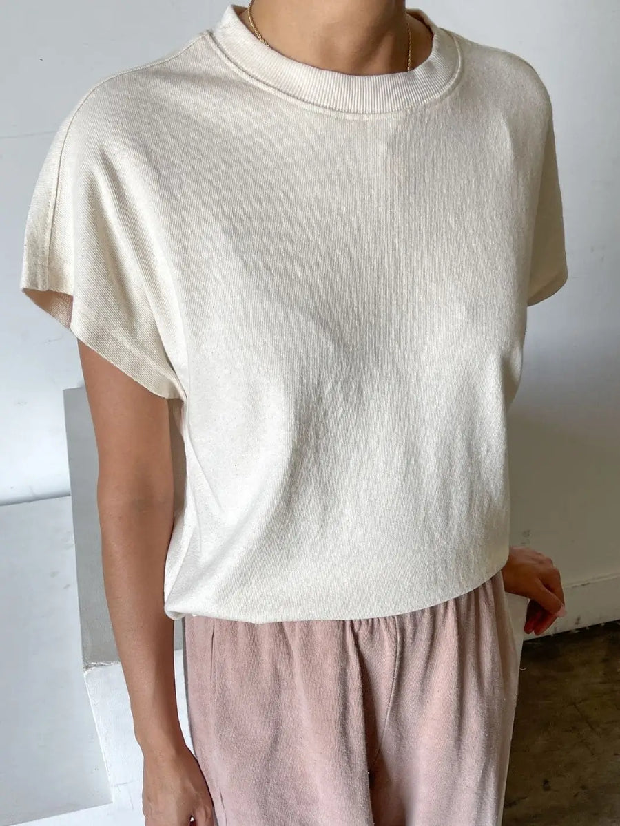 A close-up shot shows a person wearing a loose, off-white Le Bon Shoppe Jeanne Tee in Naturel paired with light pink loungewear bottoms | Twentyseven Toronto