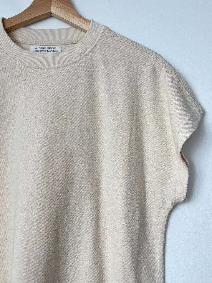 A close up of an off-white Le Bon Shoppe Jeanne Tee in Naturel with an oversized fit hanging from a wooden hanger | Twentyseven Toronto