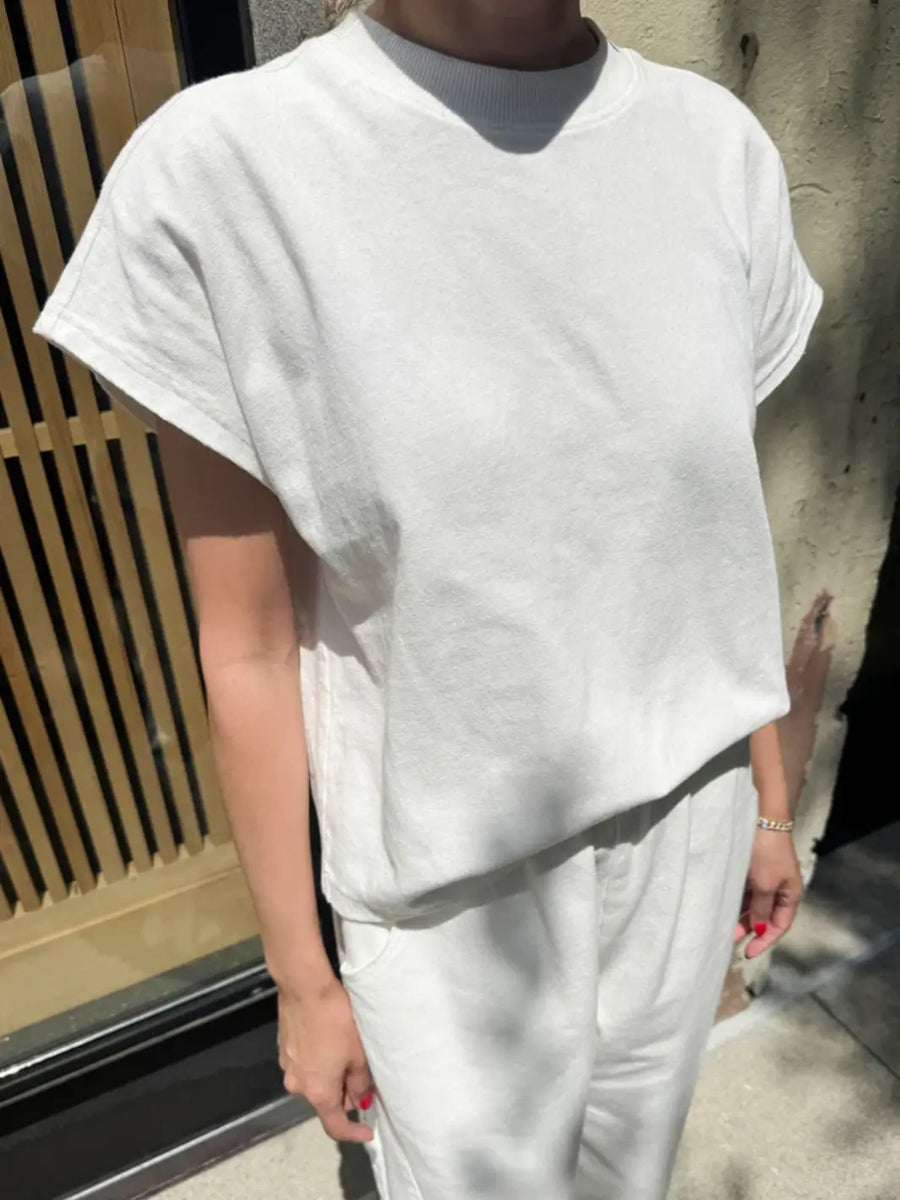 A person models the relaxed-fit Le Bon Shoppe Jeanne Tee in White Cotton outdoors, pairing it with matching white sweatpants | Twentyseven Toronto