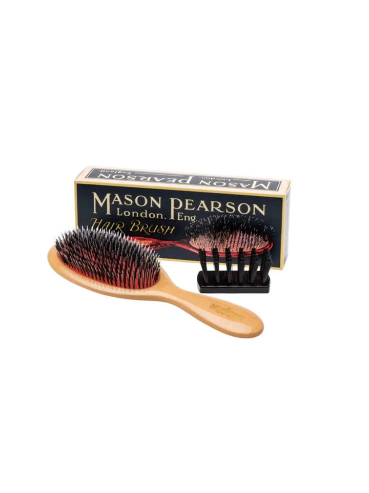 The elegant Mason Pearson Junior Lightwood Hairbrush BN2W is displayed on a white surface alongside its official navy blue product packaging and a small black cleaning brush | Twentyseven Toronto